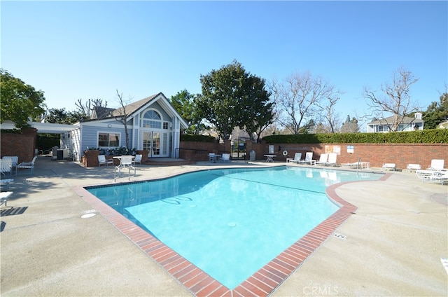 pool featuring an exterior structure, a patio, fence, and an outbuilding