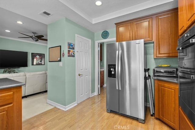 kitchen with stainless steel fridge, light wood-style floors, brown cabinets, and dark countertops