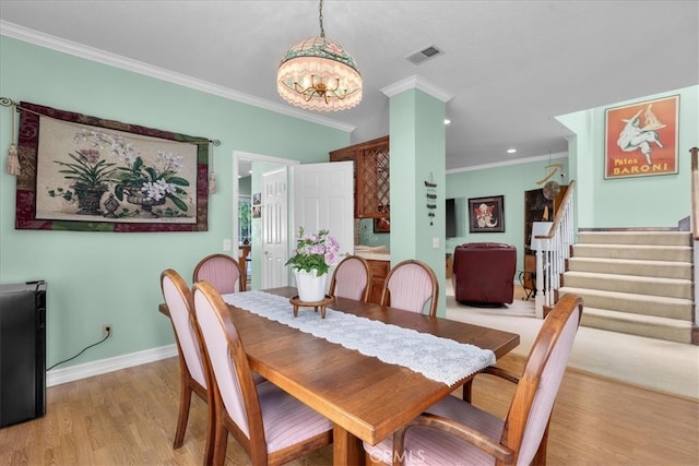 dining room featuring an inviting chandelier, ornamental molding, stairs, and visible vents