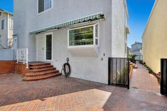 back of house with a gate and stucco siding