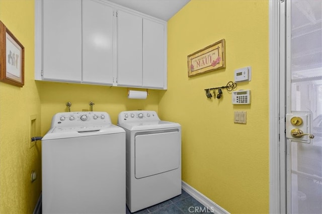 washroom featuring cabinet space, dark tile patterned flooring, baseboards, and washing machine and clothes dryer