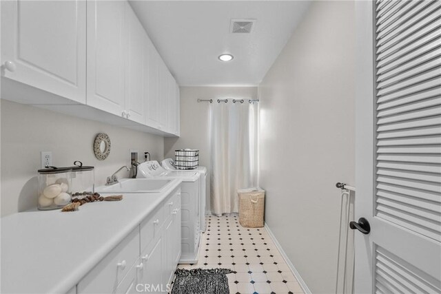 clothes washing area with visible vents, washer and dryer, baseboards, a sink, and cabinet space