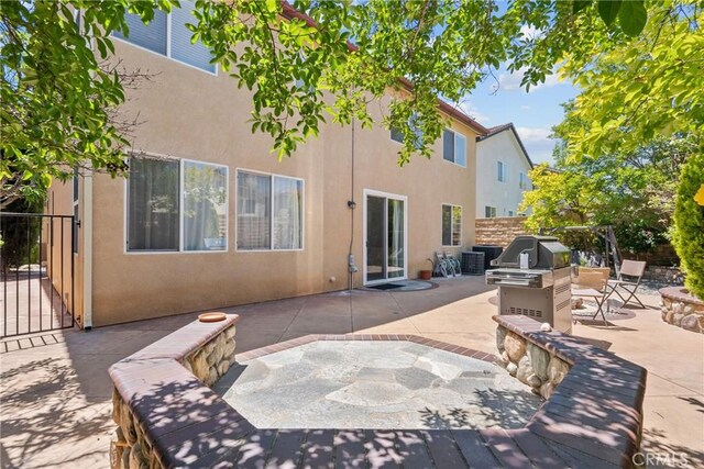 rear view of house with a patio area, stucco siding, exterior kitchen, and fence