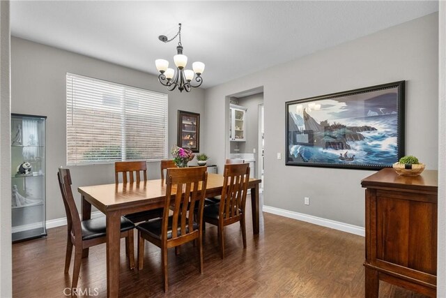 dining area with baseboards, dark wood finished floors, and a chandelier