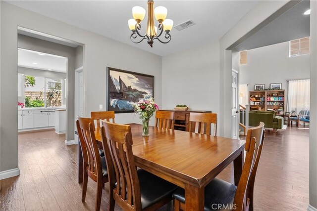 dining area featuring baseboards, a notable chandelier, wood finished floors, and visible vents