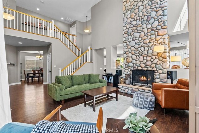 living room with a towering ceiling, a fireplace, wood finished floors, stairway, and baseboards