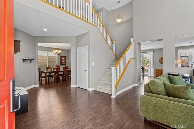 foyer entrance with stairs, baseboards, an inviting chandelier, and wood finished floors