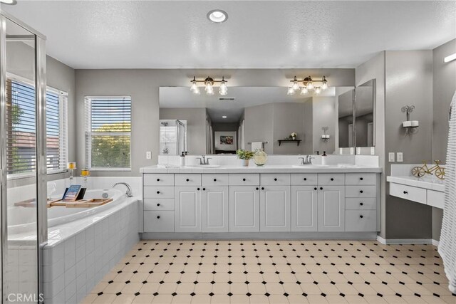 bathroom with double vanity, a sink, and a bath