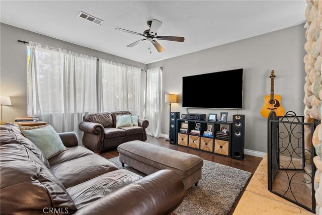 living area featuring baseboards, ceiling fan, wood finished floors, and visible vents