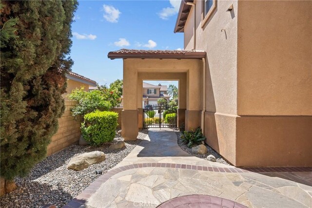 view of exterior entry with a gate and stucco siding