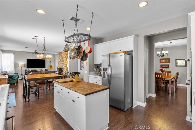 kitchen featuring stainless steel fridge with ice dispenser, a kitchen island, wooden counters, and white cabinetry