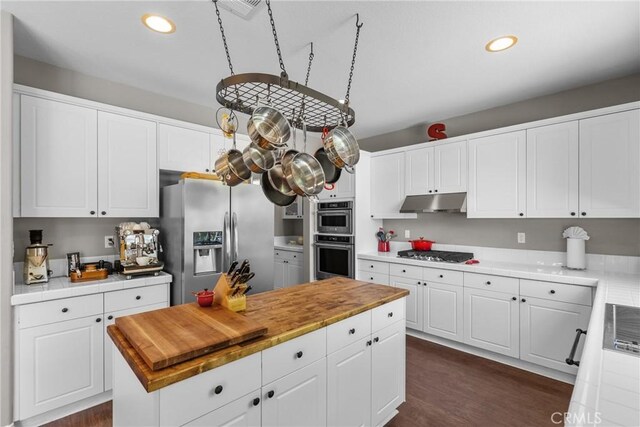 kitchen with white cabinets, dark wood-style floors, under cabinet range hood, stainless steel appliances, and recessed lighting