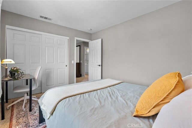 bedroom featuring carpet floors, visible vents, and a closet