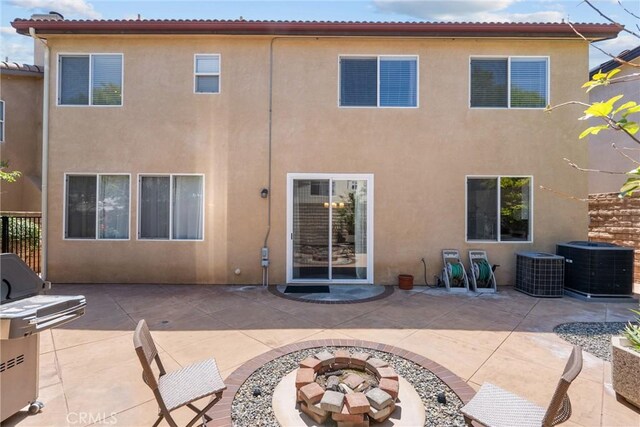 rear view of property with a patio, a fire pit, stucco siding, and central air condition unit