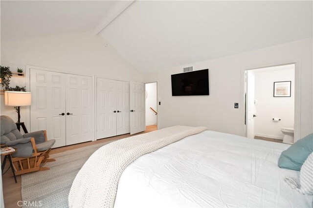 bedroom with wood finished floors, two closets, visible vents, and beamed ceiling