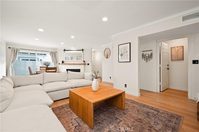 living room featuring recessed lighting, baseboards, light wood-type flooring, visible vents, and ornamental molding