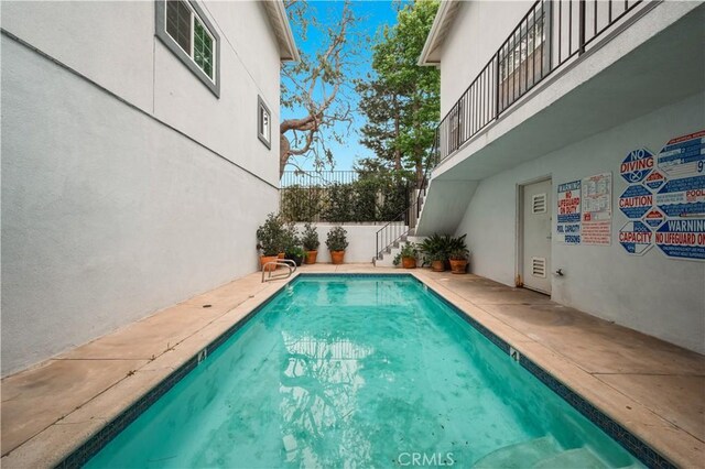 view of swimming pool featuring a fenced in pool and stairs