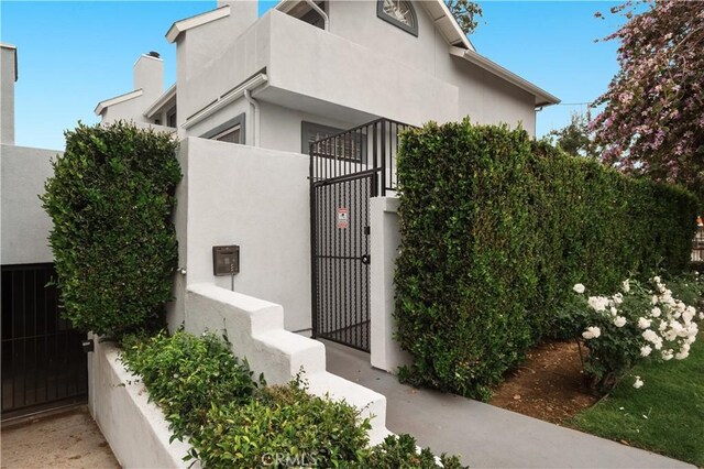 view of property exterior with fence, a gate, and stucco siding