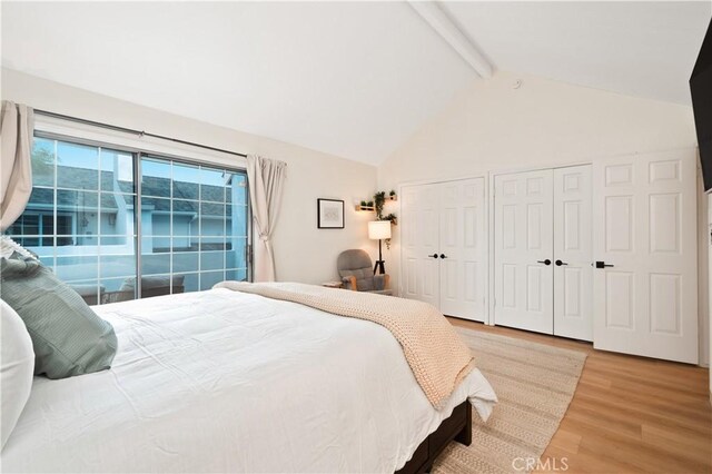 bedroom with light wood-style floors, multiple closets, high vaulted ceiling, and beamed ceiling