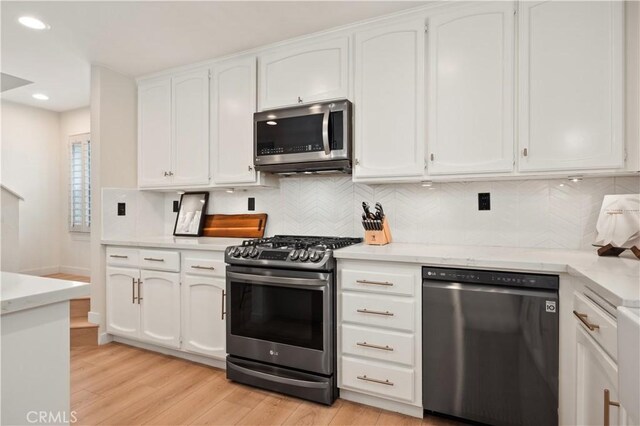 kitchen featuring light wood-style flooring, appliances with stainless steel finishes, white cabinetry, and tasteful backsplash