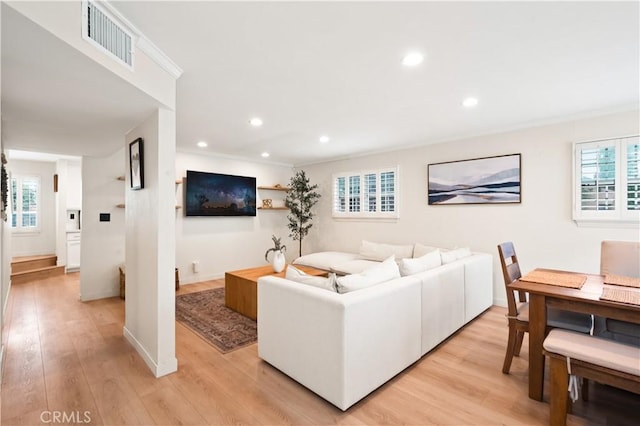 living room with visible vents, light wood-style floors, and a healthy amount of sunlight