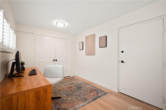 office area with baseboards and light wood finished floors