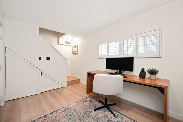 office space with baseboards and light wood-style floors