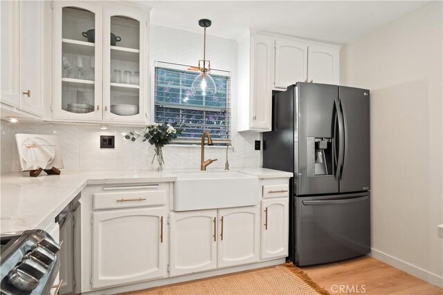 kitchen featuring stainless steel fridge, tasteful backsplash, a sink, and white cabinets