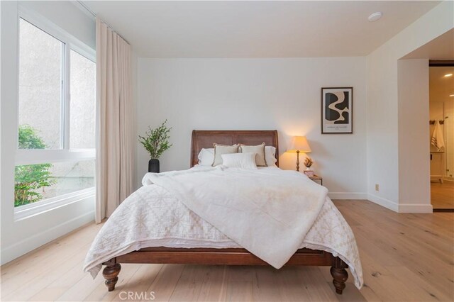 bedroom featuring baseboards, multiple windows, and light wood-style flooring