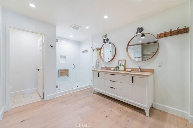 bathroom featuring a stall shower, visible vents, a sink, and wood finished floors