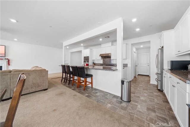 6506 Zion Way, Jurupa Valley, CA 92509 - kitchen with stainless steel appliances, under cabinet range hood, a kitchen bar, open floor plan, and white cabinetry