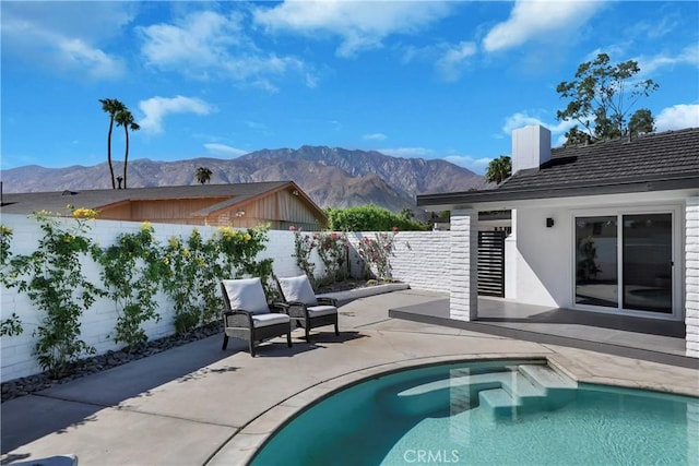 view of swimming pool featuring a fenced backyard, a fenced in pool, a patio, and a mountain view