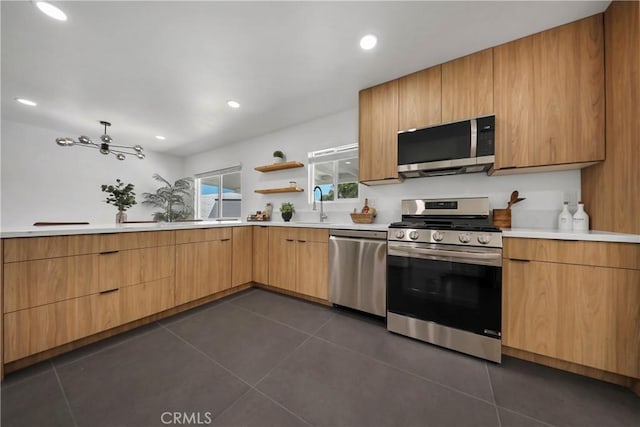 kitchen with a sink, light countertops, dark tile patterned flooring, and stainless steel appliances