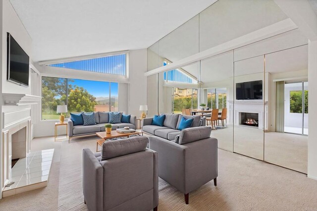 1109 Calle Del Baston, San Marcos, CA 92078 - living room with a lit fireplace, light colored carpet, and high vaulted ceiling
