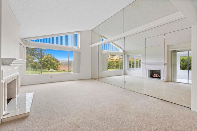 1109 Calle Del Baston, San Marcos, CA 92078 - unfurnished living room with a lit fireplace, carpet floors, healthy amount of natural light, and high vaulted ceiling
