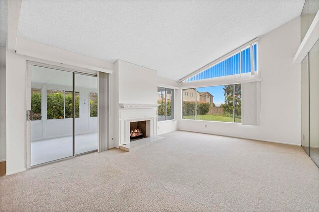 1109 Calle Del Baston, San Marcos, CA 92078 - unfurnished living room featuring carpet flooring, a textured ceiling, a lit fireplace, and lofted ceiling