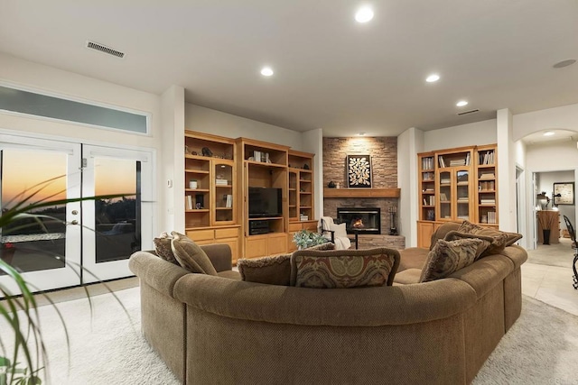 living room featuring visible vents, recessed lighting, arched walkways, and a stone fireplace