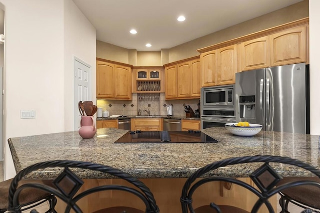 kitchen with a breakfast bar, glass insert cabinets, recessed lighting, tasteful backsplash, and appliances with stainless steel finishes