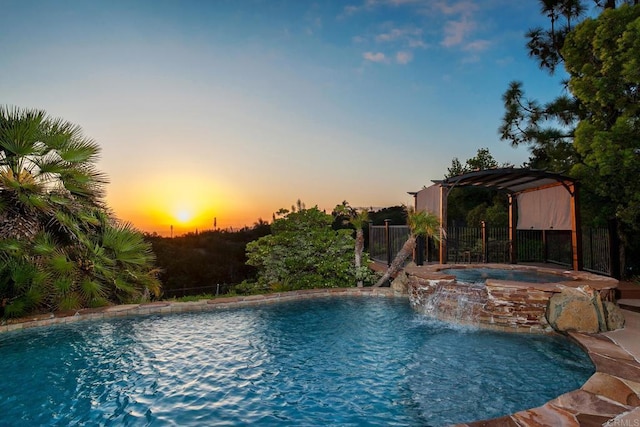 view of pool featuring fence and a pool with connected hot tub