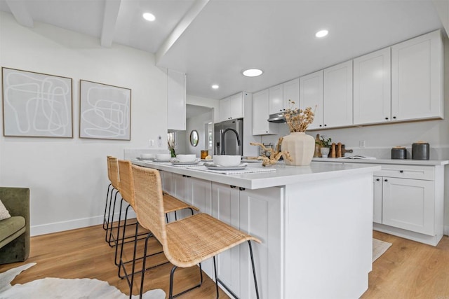 5061 Canosa Ave, San Diego, CA 92117 - kitchen featuring light wood-type flooring, light countertops, white cabinetry, and a breakfast bar area