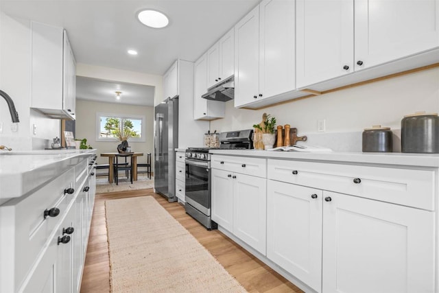 5061 Canosa Ave, San Diego, CA 92117 - kitchen featuring white cabinets, appliances with stainless steel finishes, light countertops, light wood-style flooring, and under cabinet range hood