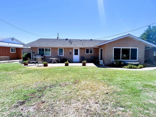 rear view of property with a patio, stucco siding, and a yard