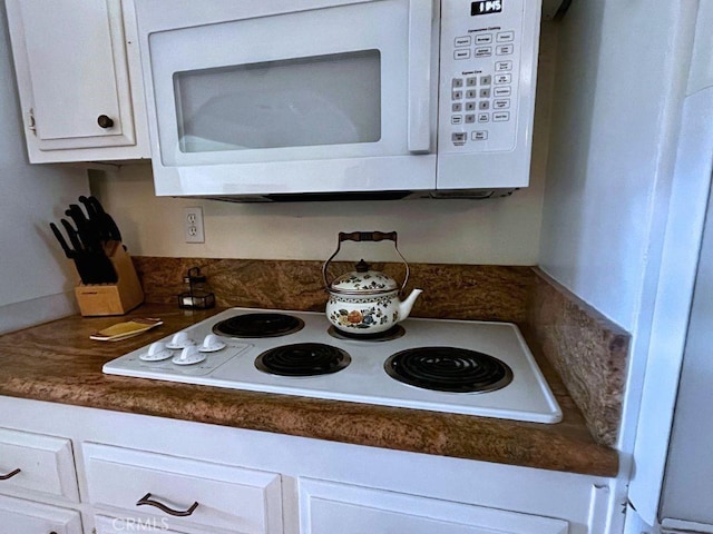 room details with dark countertops, white appliances, and white cabinetry