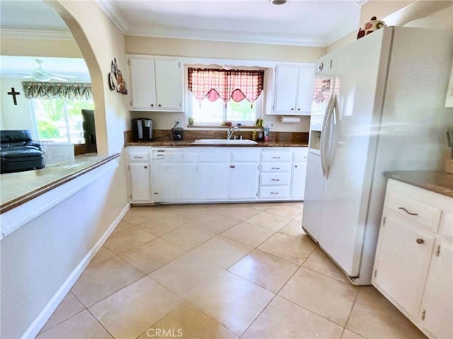kitchen featuring crown molding, a healthy amount of sunlight, white refrigerator with ice dispenser, white cabinetry, and a sink