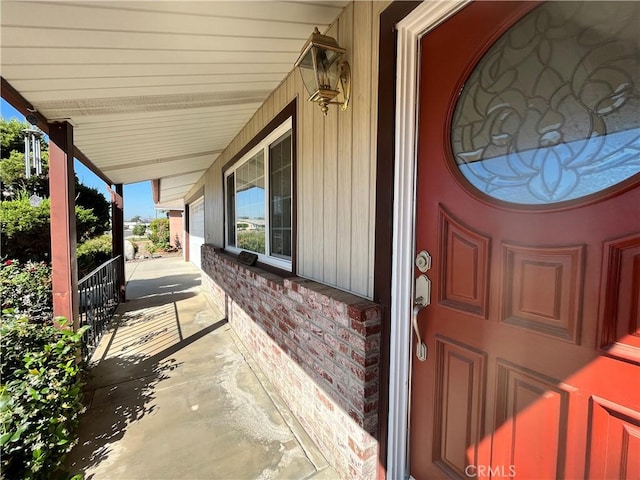 doorway to property featuring brick siding and covered porch
