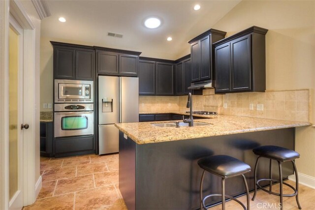 kitchen with visible vents, a peninsula, decorative backsplash, and appliances with stainless steel finishes