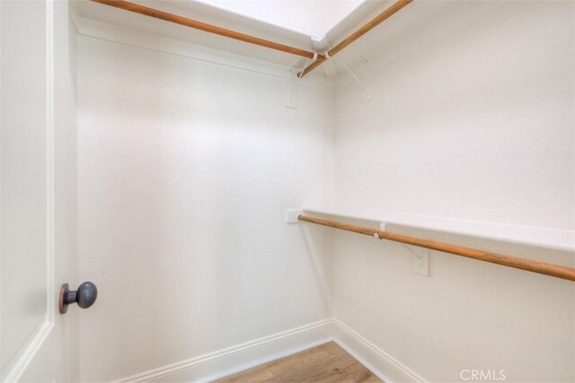 walk in closet with light wood finished floors