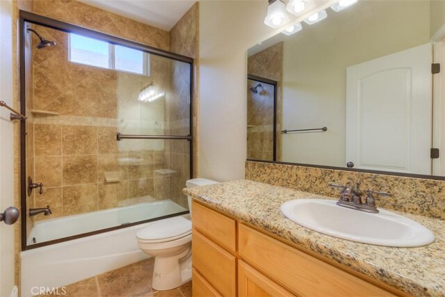 full bath featuring vanity, enclosed tub / shower combo, tile patterned flooring, and toilet