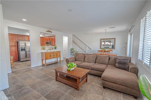 living room featuring an inviting chandelier, a healthy amount of sunlight, stairway, and visible vents