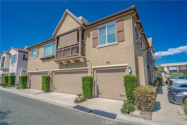 multi unit property with a garage, stucco siding, and a balcony